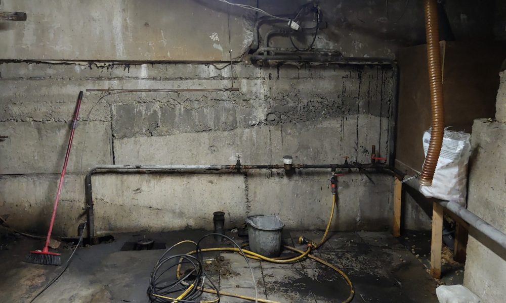Basement renovation process. Dark dirty room with pipes