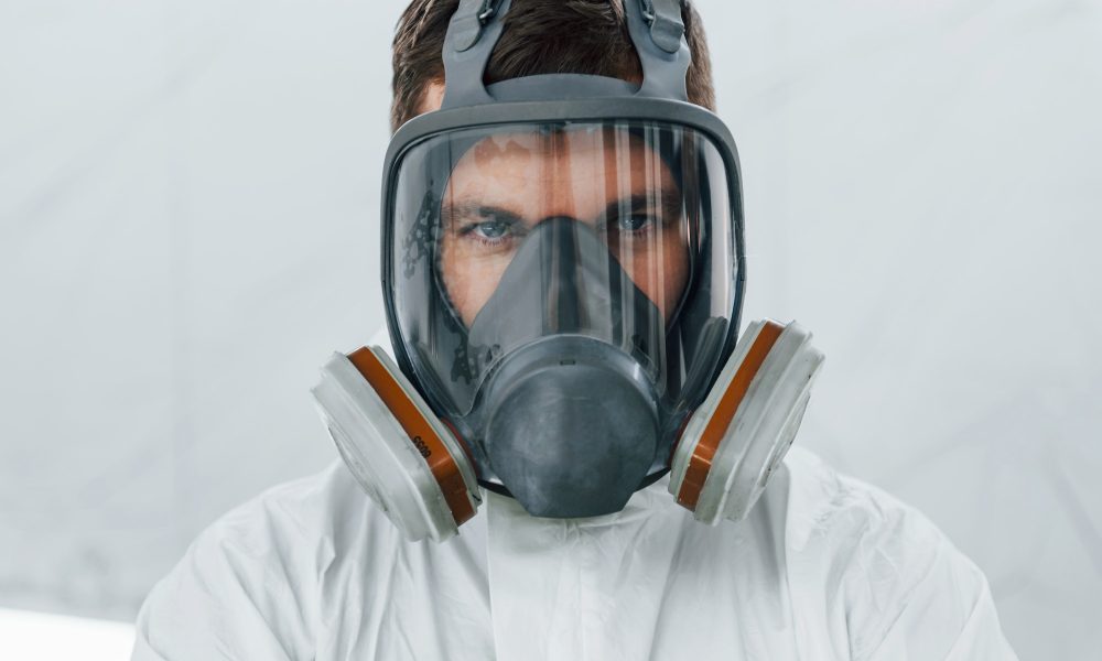 Portrait of man in the protective mask. Worker in uniform is in the auto service