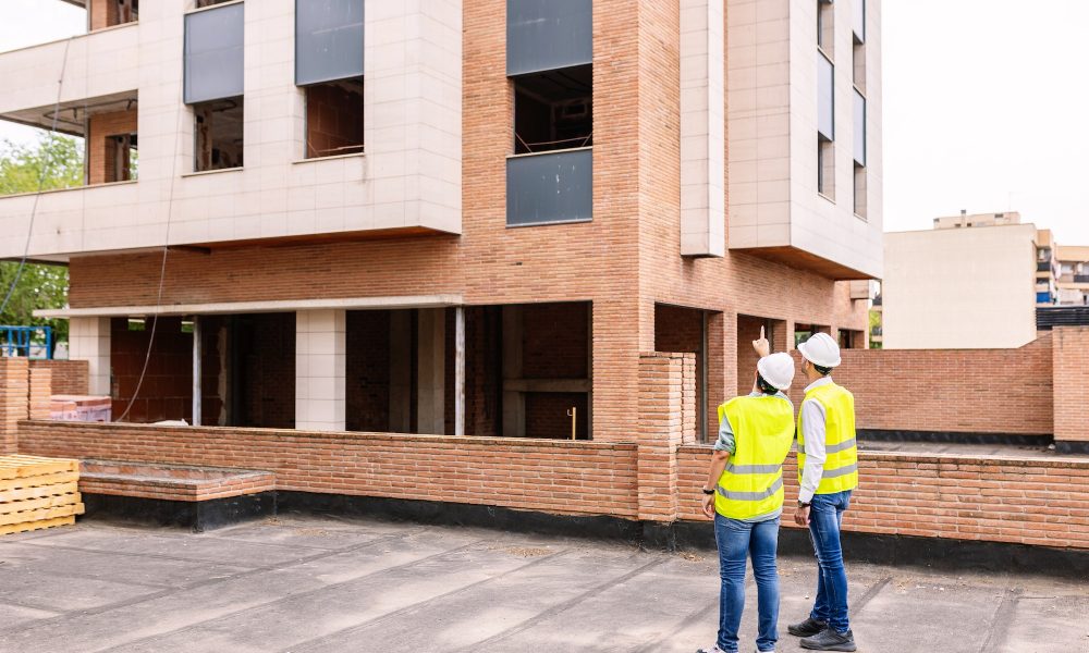 Professional engineers architect workers talking at building construction site