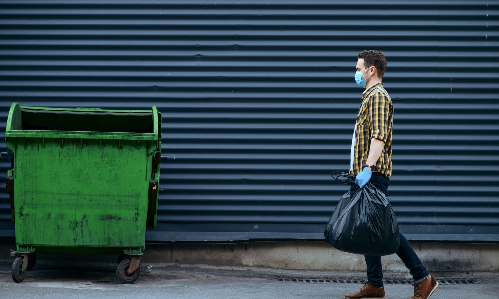 Volunteer carries plastic trash bags to the can