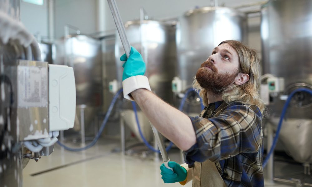Worker Cleaning Machines at Factory